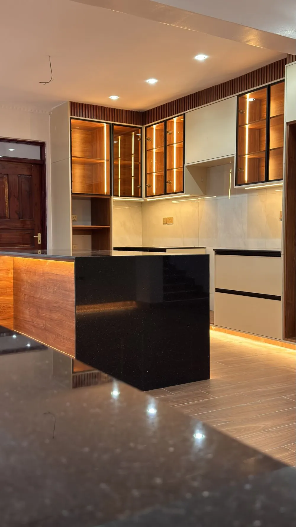 Display cabinets and island seen across a granite worktop