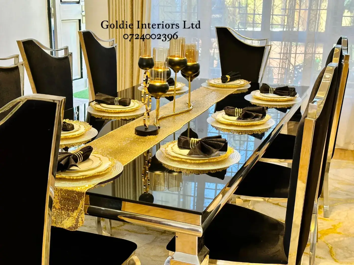 Close view of the dining table laid with gold-rimmed plates, black napkins with gold rings, a sequin runner and black-and-gold candle holders