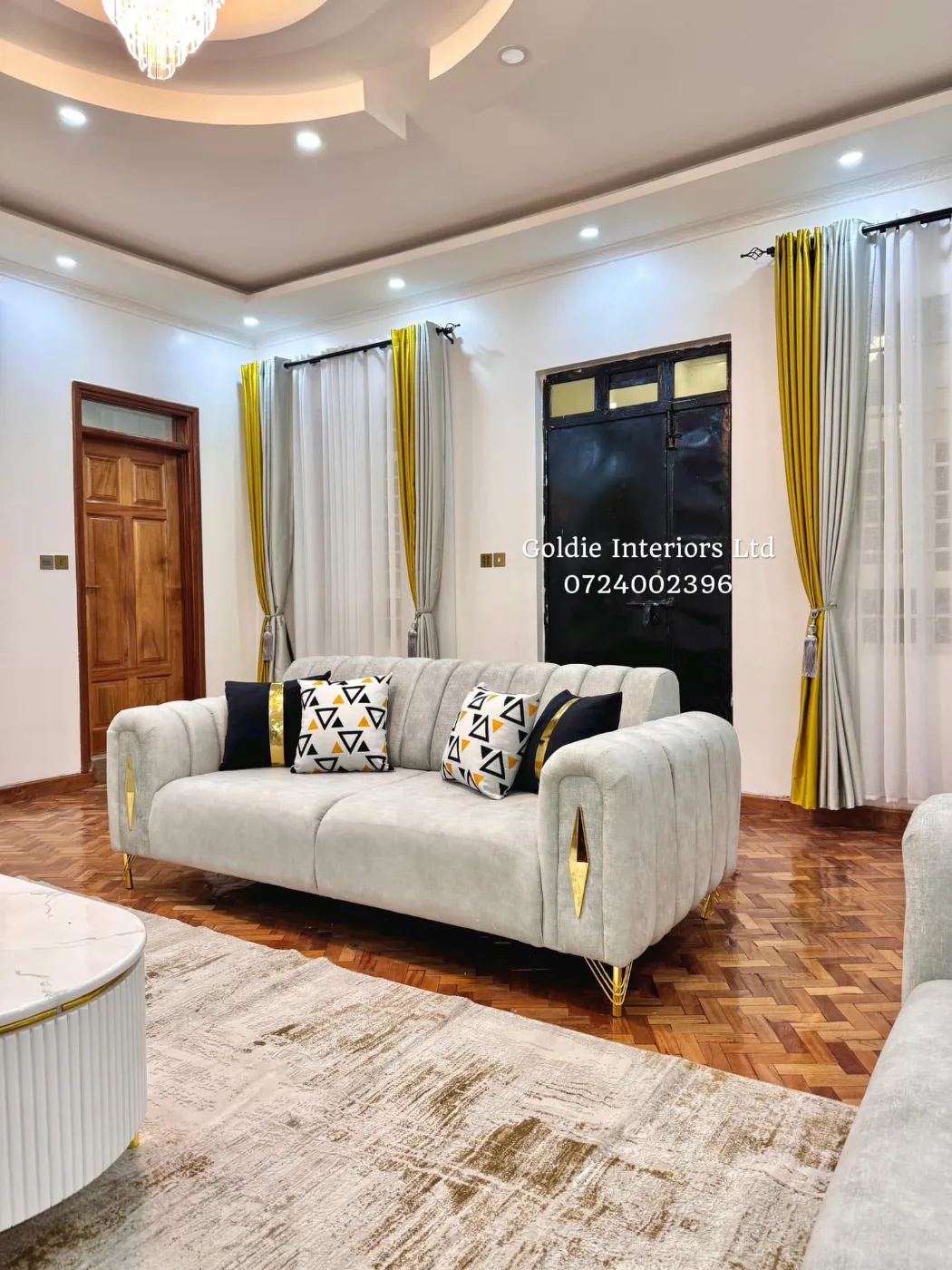 Pale grey channel-tufted sofa with black-and-white cushions, a fluted white coffee table and mustard curtains