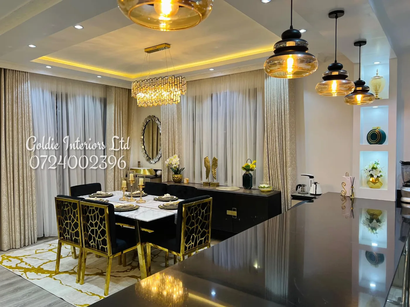 Dining area with a marble-top table, gold-and-black patterned chairs and glass pendants, seen across a black counter