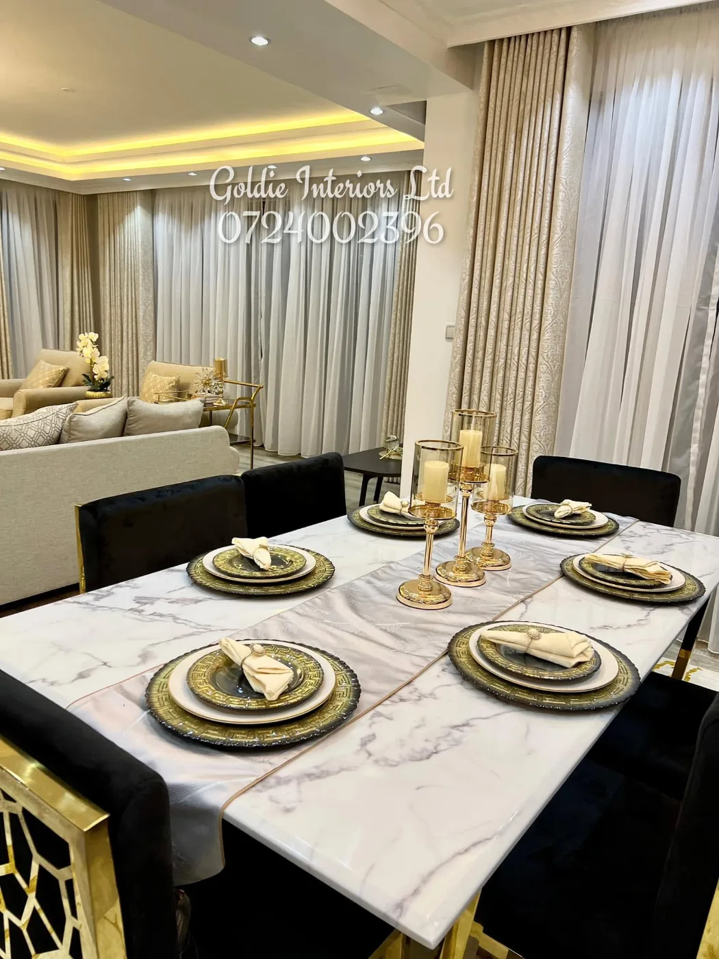 Marble-top dining table laid with gold-rimmed plates, candle holders and napkins