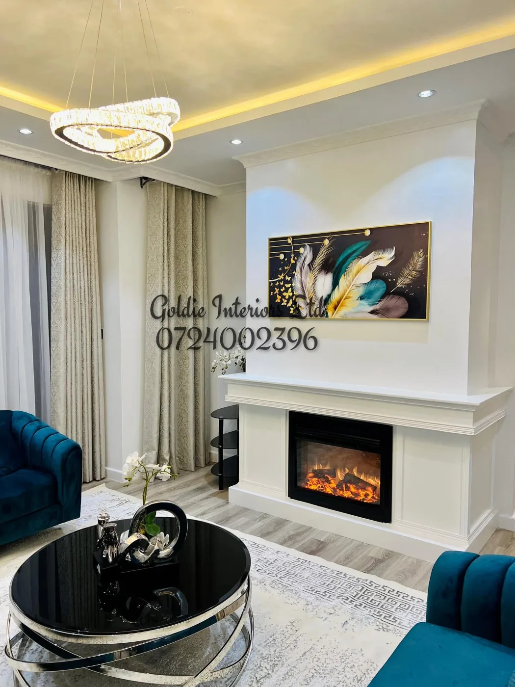 Private lounge with an electric fireplace and mantel, a feather-pattern painting and a teal velvet sofa