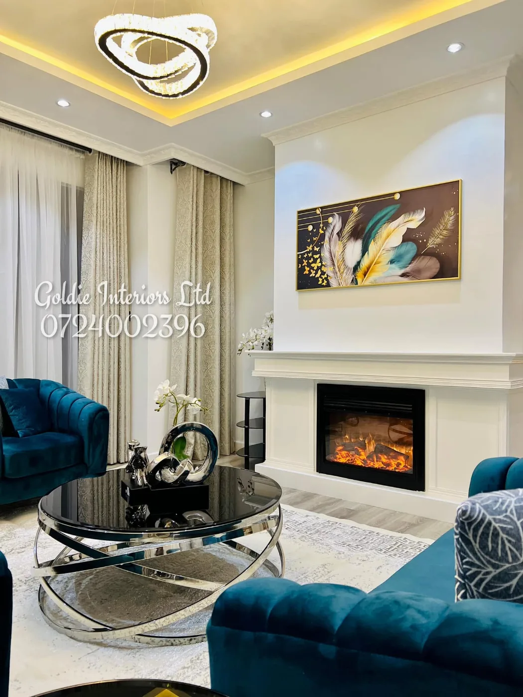 Lounge with a teal sofa, a black-and-chrome round coffee table and a fireplace below a ring-shaped light