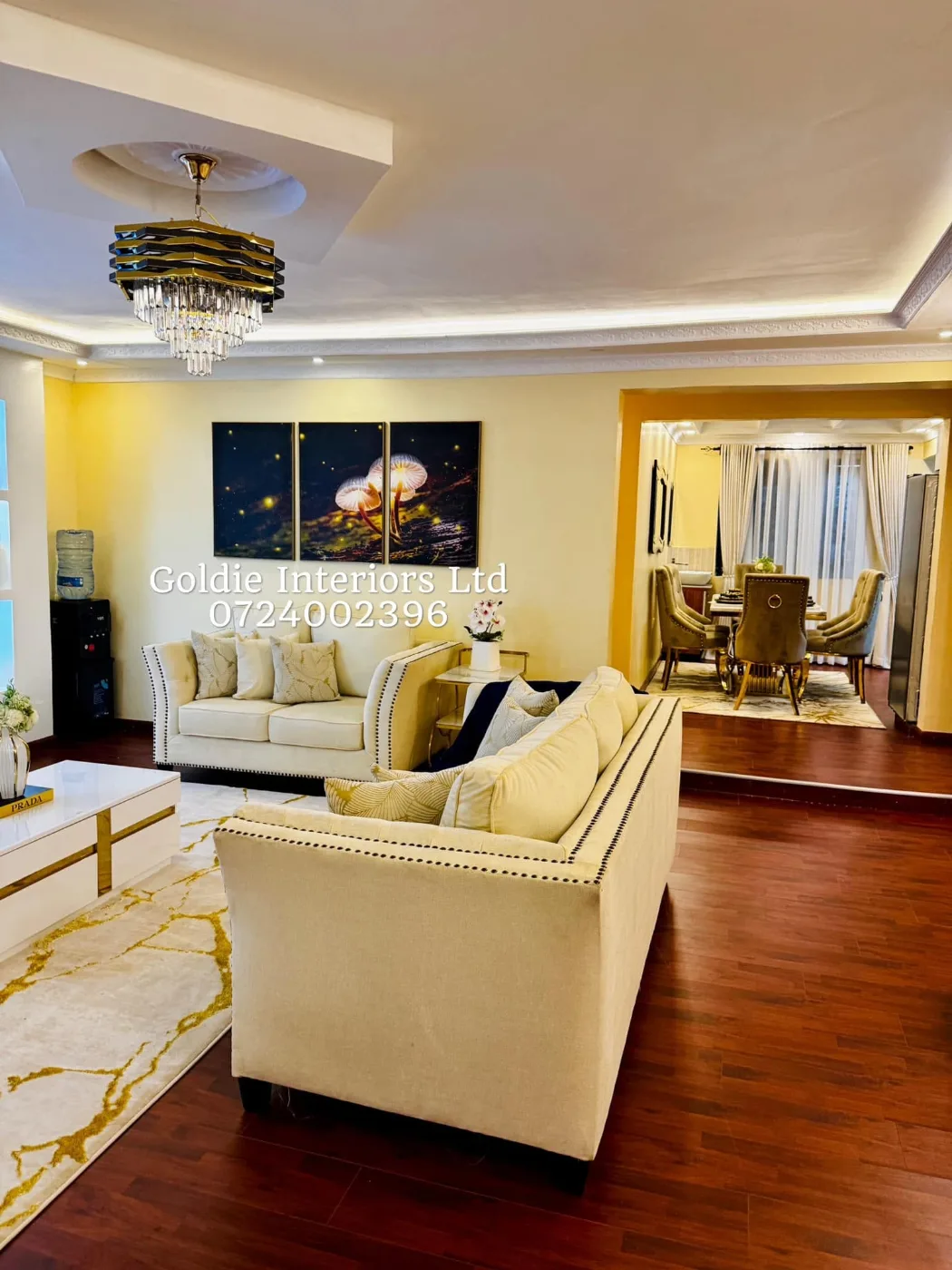 Living room with cream sofas facing a triptych of glowing mushrooms, with the dining area visible beyond a step and an arch