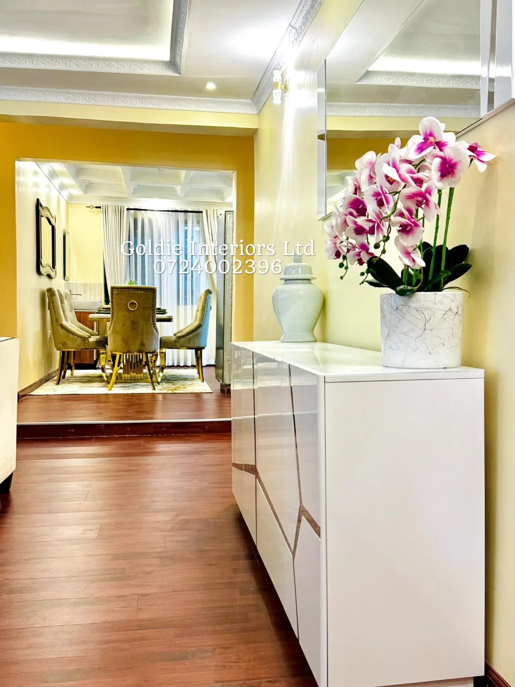 White buffet cabinet with a ginger jar and a pink orchid in a marble-effect pot, looking through to the dining area